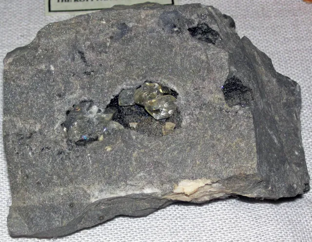 A slab of gray dolostone with a cavity holding clear, double-pointed quartz crystals