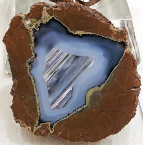 A cut thunderegg with a rough brown rind around a cavity filled with blue-gray banded agate