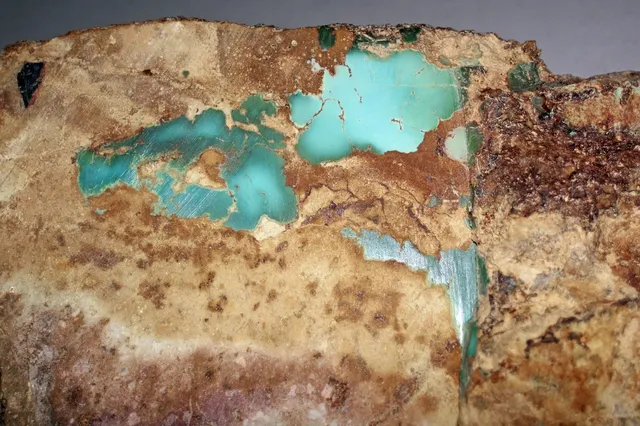 Blue-green turquoise veins and patches in tan and brown host rock